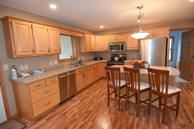 kitchen featuring appliances with stainless steel finishes, light wood-type flooring, hanging light fixtures, and sink