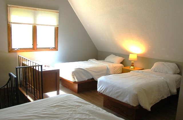 bedroom with vaulted ceiling and hardwood / wood-style flooring