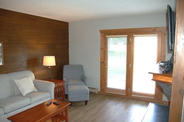 living room featuring wood walls, light hardwood / wood-style flooring, and a baseboard radiator