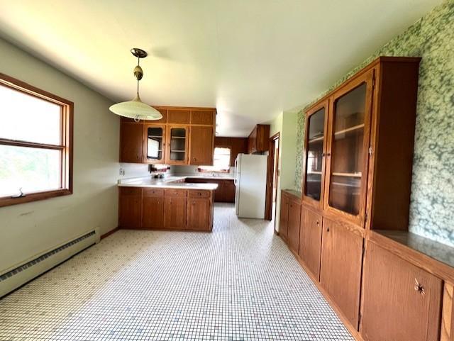 kitchen with a baseboard heating unit, hanging light fixtures, white refrigerator, kitchen peninsula, and light tile floors