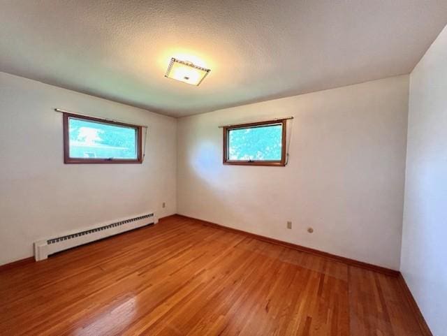 spare room featuring a baseboard heating unit and wood-type flooring