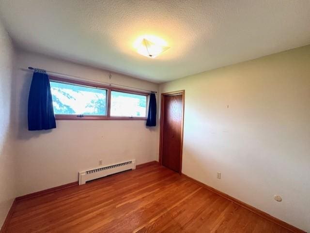 unfurnished room featuring hardwood / wood-style floors and a baseboard radiator