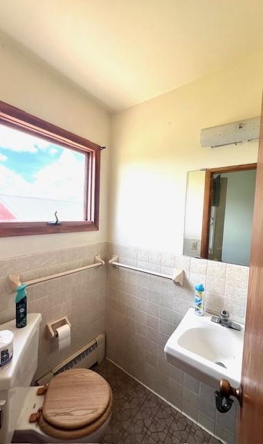 bathroom with tile walls, toilet, and tile floors