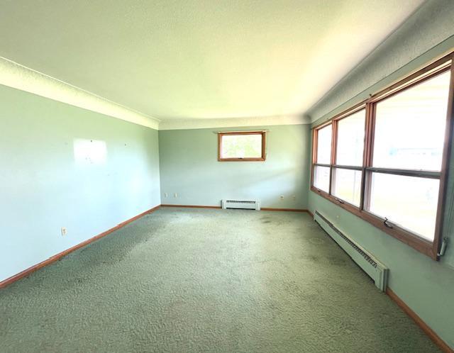 spare room featuring carpet flooring and baseboard heating