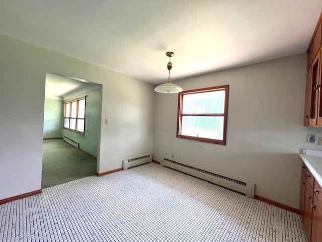 unfurnished dining area featuring carpet flooring, baseboard heating, and a healthy amount of sunlight