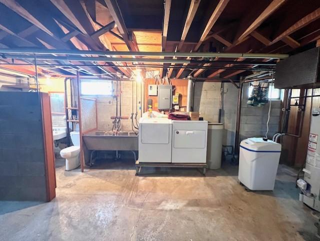 basement with sink, water heater, and washing machine and clothes dryer