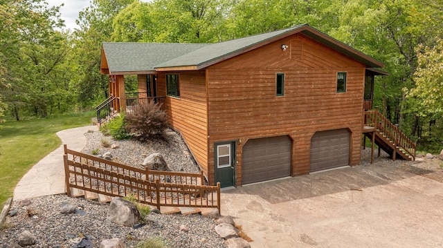 view of side of home with an attached garage, a shingled roof, and concrete driveway