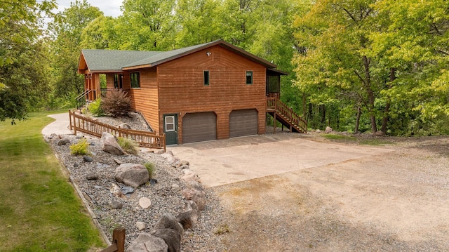 view of home's exterior with an attached garage, a forest view, stairs, and concrete driveway