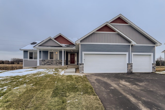 craftsman-style house with covered porch, a garage, and a front lawn