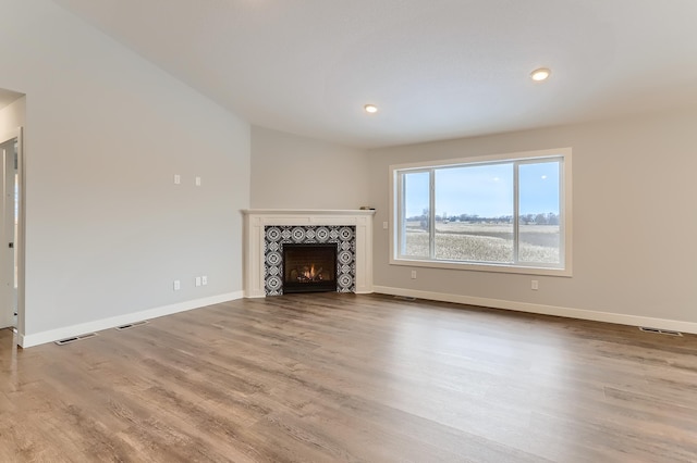 unfurnished living room with light hardwood / wood-style flooring and a tiled fireplace