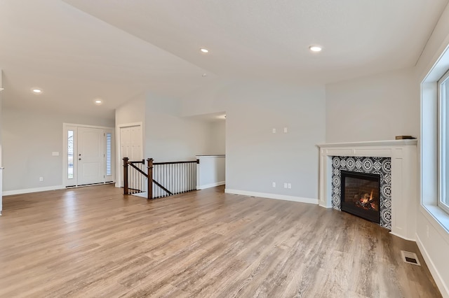 unfurnished living room with a fireplace, light hardwood / wood-style floors, and lofted ceiling