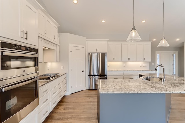 kitchen with appliances with stainless steel finishes, an island with sink, pendant lighting, and sink