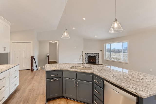 kitchen featuring dishwasher, a center island with sink, sink, light hardwood / wood-style floors, and white cabinetry