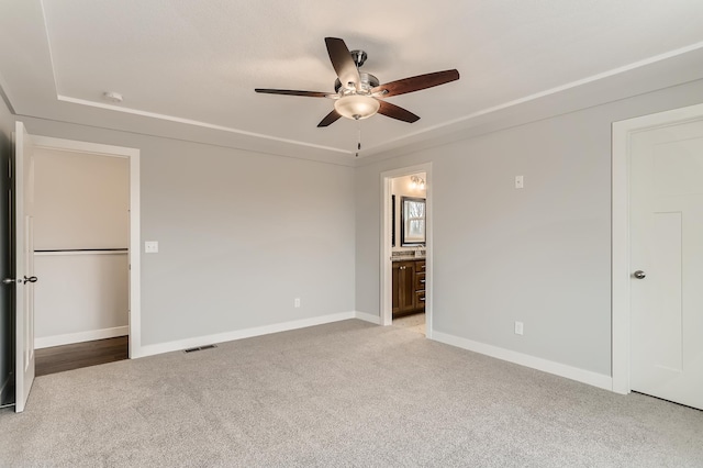 unfurnished bedroom with light carpet, connected bathroom, and ceiling fan