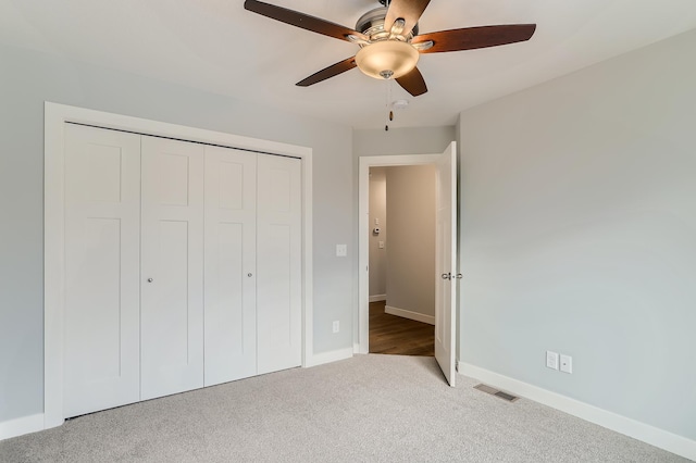 unfurnished bedroom featuring ceiling fan, light colored carpet, and a closet