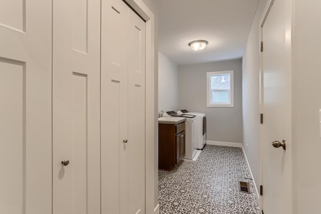 laundry area featuring washer and dryer, cabinets, and a textured ceiling