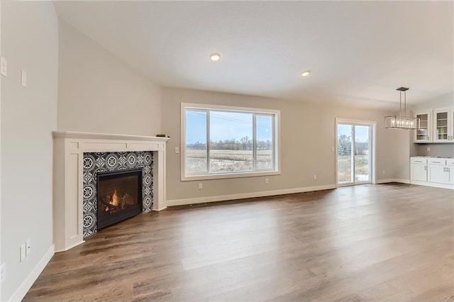 unfurnished living room featuring a tile fireplace and hardwood / wood-style flooring