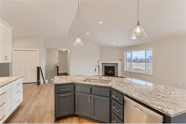 kitchen featuring sink, stainless steel dishwasher, a center island with sink, white cabinets, and light wood-type flooring