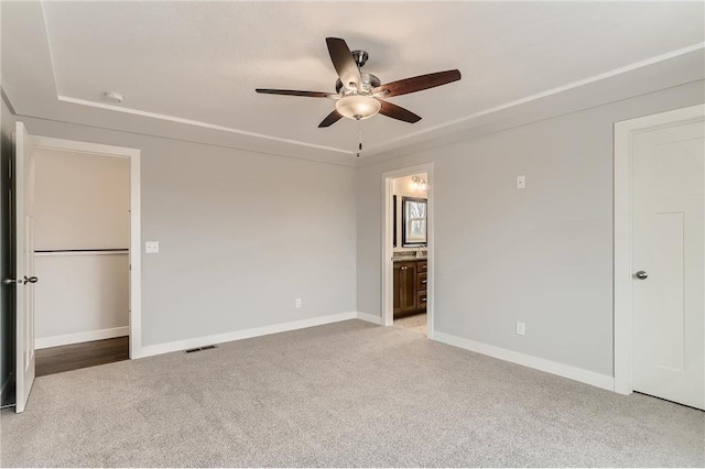 unfurnished bedroom with ensuite bath, light carpet, and ceiling fan