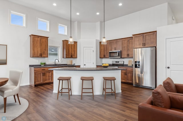 kitchen featuring brown cabinets, dark countertops, a kitchen bar, and stainless steel appliances
