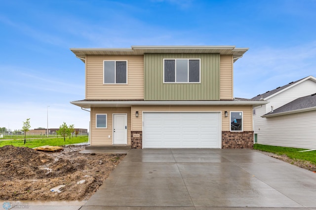 traditional home with a garage, brick siding, driveway, and board and batten siding