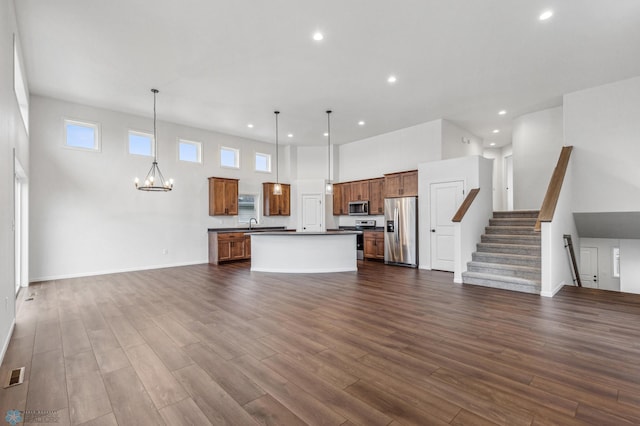 kitchen featuring an inviting chandelier, dark wood-style flooring, open floor plan, dark countertops, and stainless steel appliances