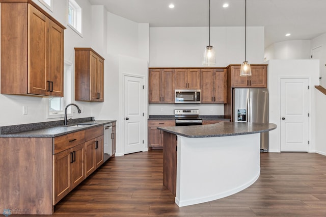 kitchen with a high ceiling, a sink, appliances with stainless steel finishes, dark wood finished floors, and brown cabinets