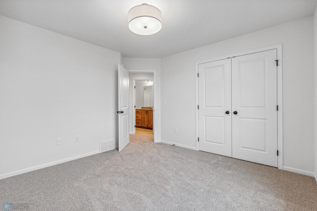 unfurnished bedroom with a closet, baseboards, visible vents, and carpet floors