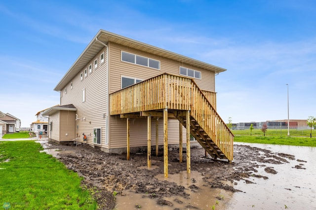 back of house with stairway, a deck, and a lawn