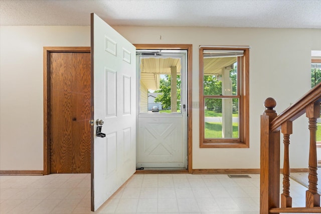 foyer entrance featuring light tile flooring and a textured ceiling