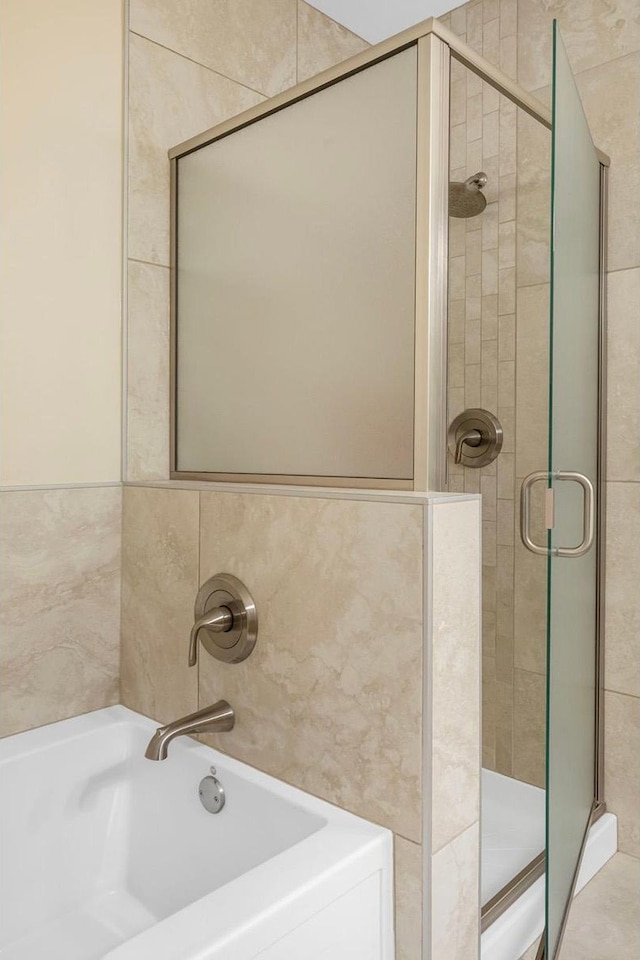 bathroom with tile walls and shower with separate bathtub