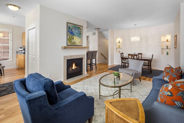 living room featuring a fireplace, a notable chandelier, and light hardwood / wood-style floors