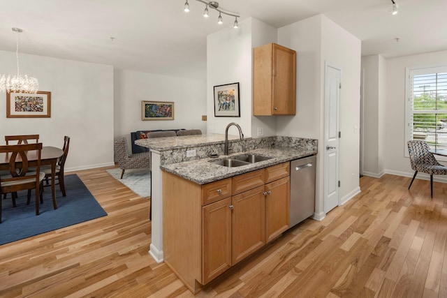 kitchen featuring dishwasher, light hardwood / wood-style flooring, light stone counters, a chandelier, and sink