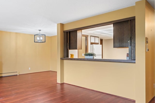 empty room with hardwood / wood-style flooring, baseboard heating, and a chandelier