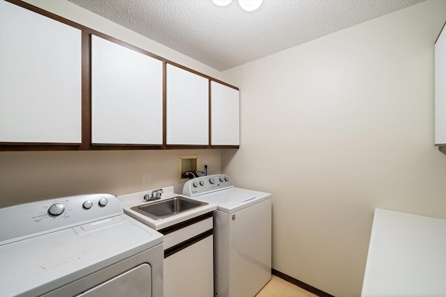 clothes washing area featuring washing machine and clothes dryer, sink, cabinets, and a textured ceiling