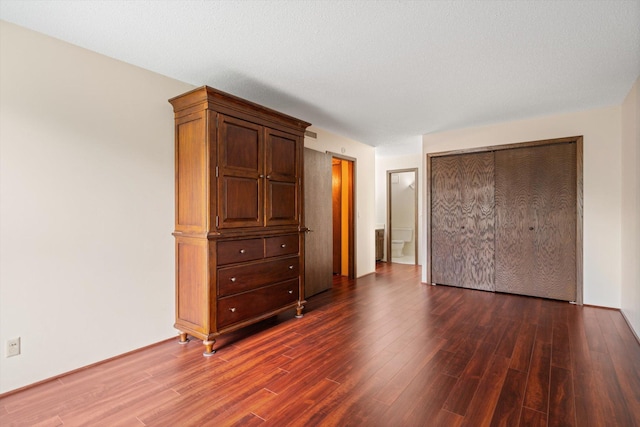 unfurnished bedroom featuring a closet, dark hardwood / wood-style flooring, and a textured ceiling