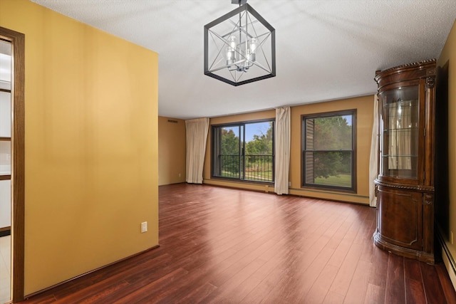 unfurnished living room with dark hardwood / wood-style flooring, a textured ceiling, and an inviting chandelier