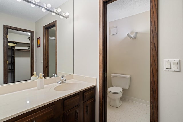 bathroom with tile patterned floors, vanity, a textured ceiling, and toilet