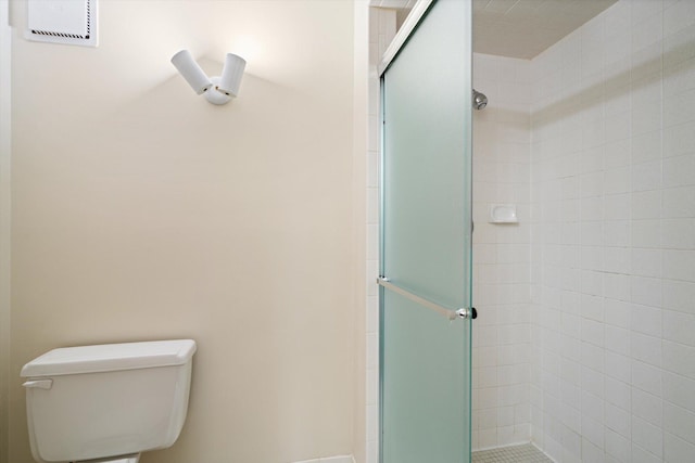 bathroom featuring toilet and a shower with shower door