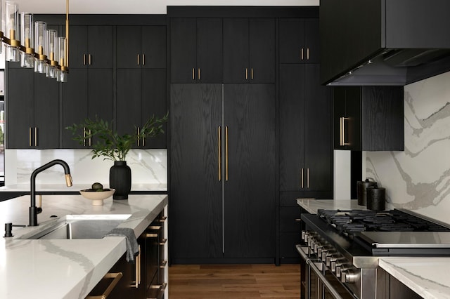 kitchen featuring extractor fan, pendant lighting, tasteful backsplash, hardwood / wood-style flooring, and light stone counters