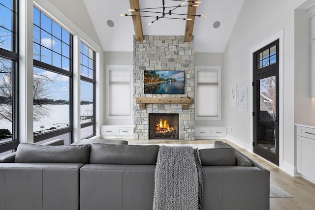 living room with an inviting chandelier, beam ceiling, high vaulted ceiling, a fireplace, and light wood-type flooring