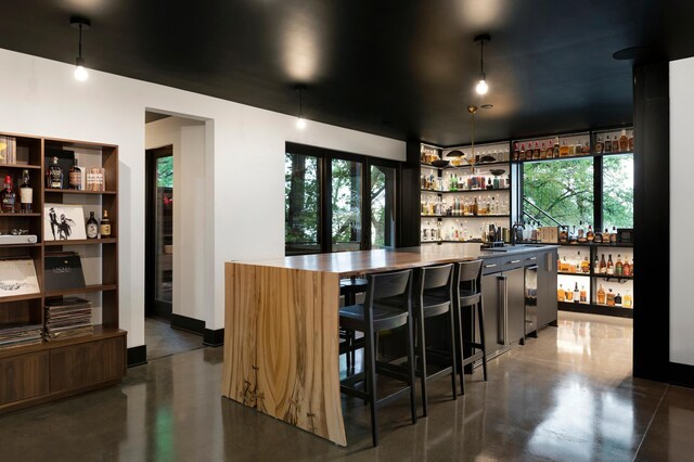 bar featuring hanging light fixtures and a wealth of natural light