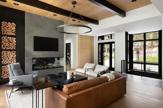 living room featuring beam ceiling, wood finished floors, wood ceiling, and a large fireplace