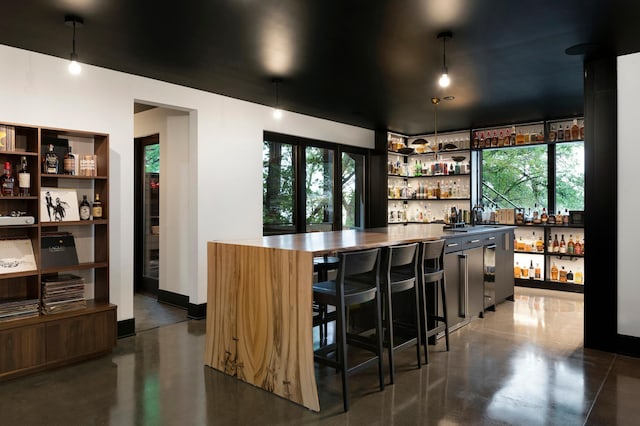indoor wet bar featuring concrete floors and pendant lighting