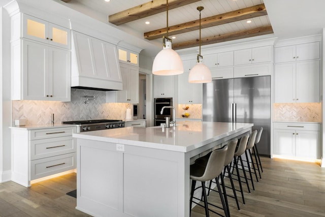 kitchen featuring stainless steel appliances, white cabinetry, a large island with sink, recessed lighting, and light wood finished floors