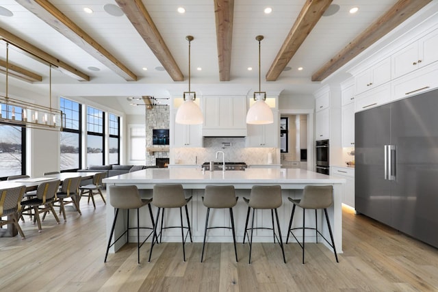 kitchen featuring appliances with stainless steel finishes, backsplash, a sink, light countertops, and beam ceiling
