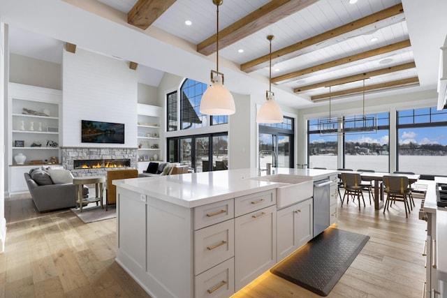 kitchen with stainless steel dishwasher, a fireplace, a sink, wood ceiling, and light countertops