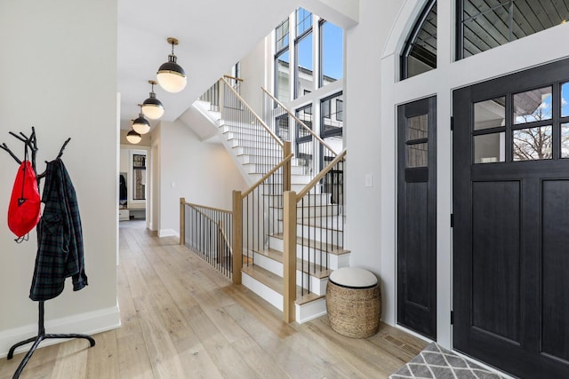 foyer entrance featuring stairway, light wood finished floors, and baseboards