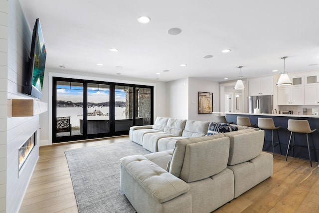living area featuring light wood-style floors, recessed lighting, and a fireplace