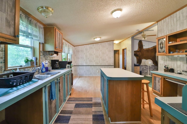 kitchen featuring a center island, sink, dark hardwood / wood-style floors, wood walls, and ceiling fan